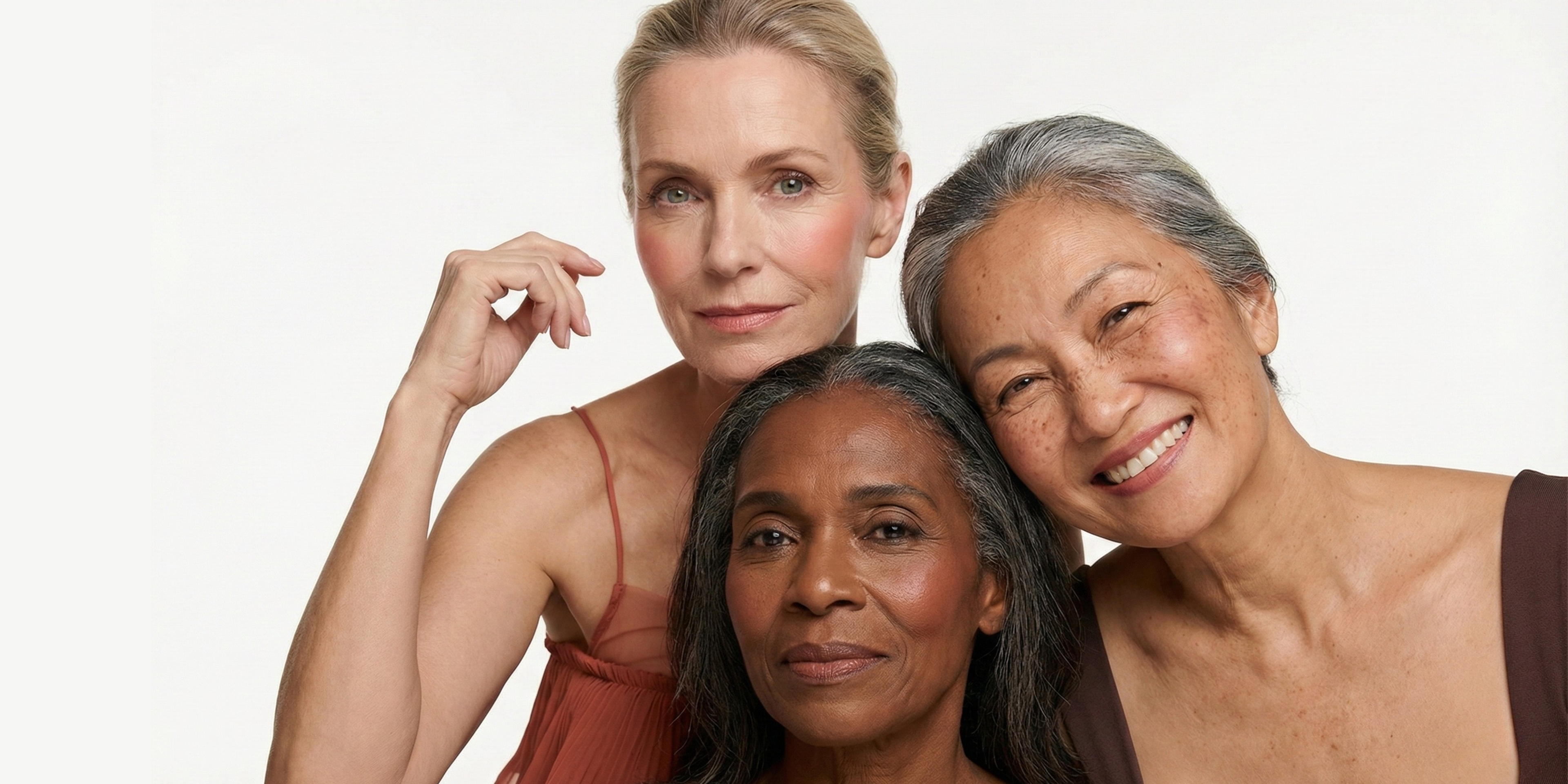 Three women of different ethnicities standing close together against a white background